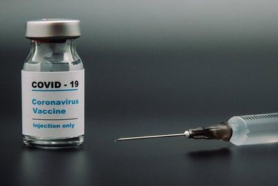Vial of COVID-19 vaccine next a needle